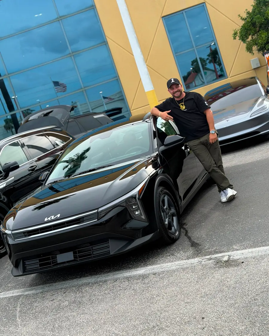 A Tier client beside the vehicle he has just picked up at the dealership.