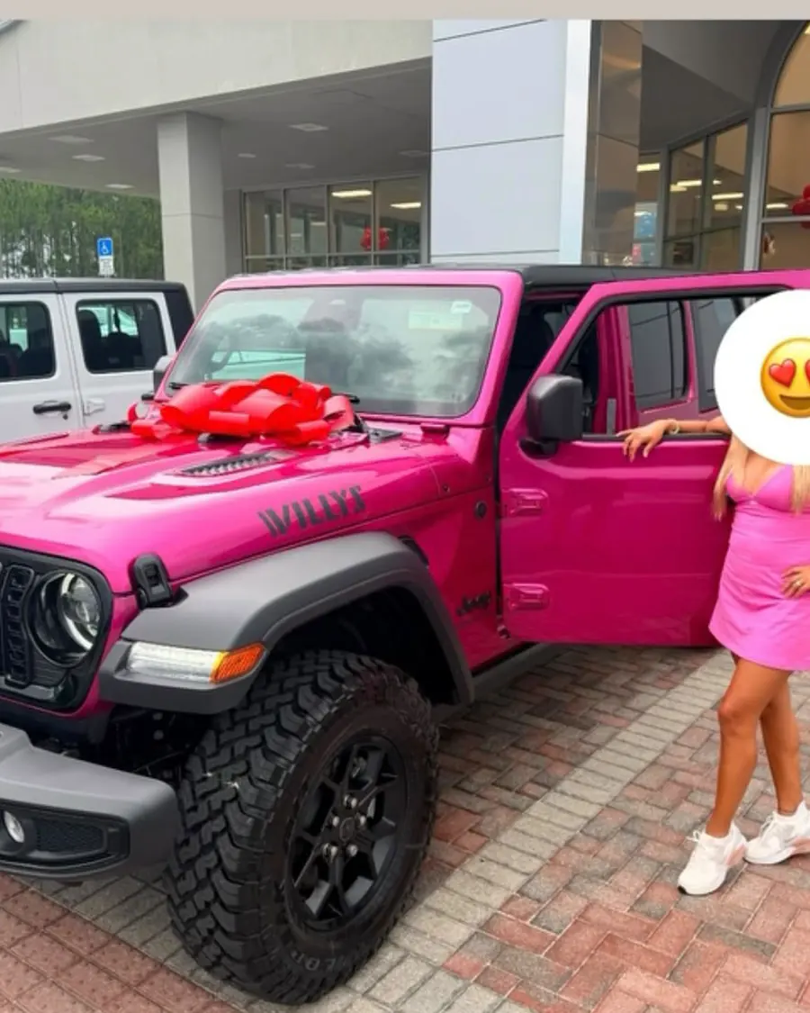 A Tier client beside her new vehicle with a bow on the hood.