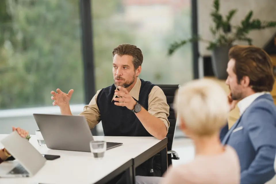 A working meeting in a bright room: someone explaining with their hands while the others listen.